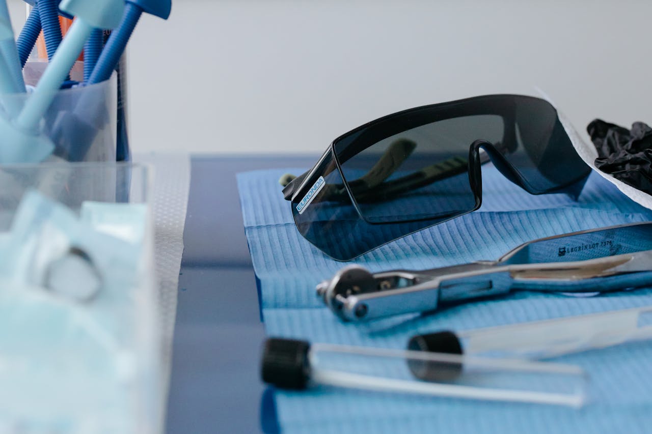 Close-up of dental tools and protective goggles on a blue dental table mat.