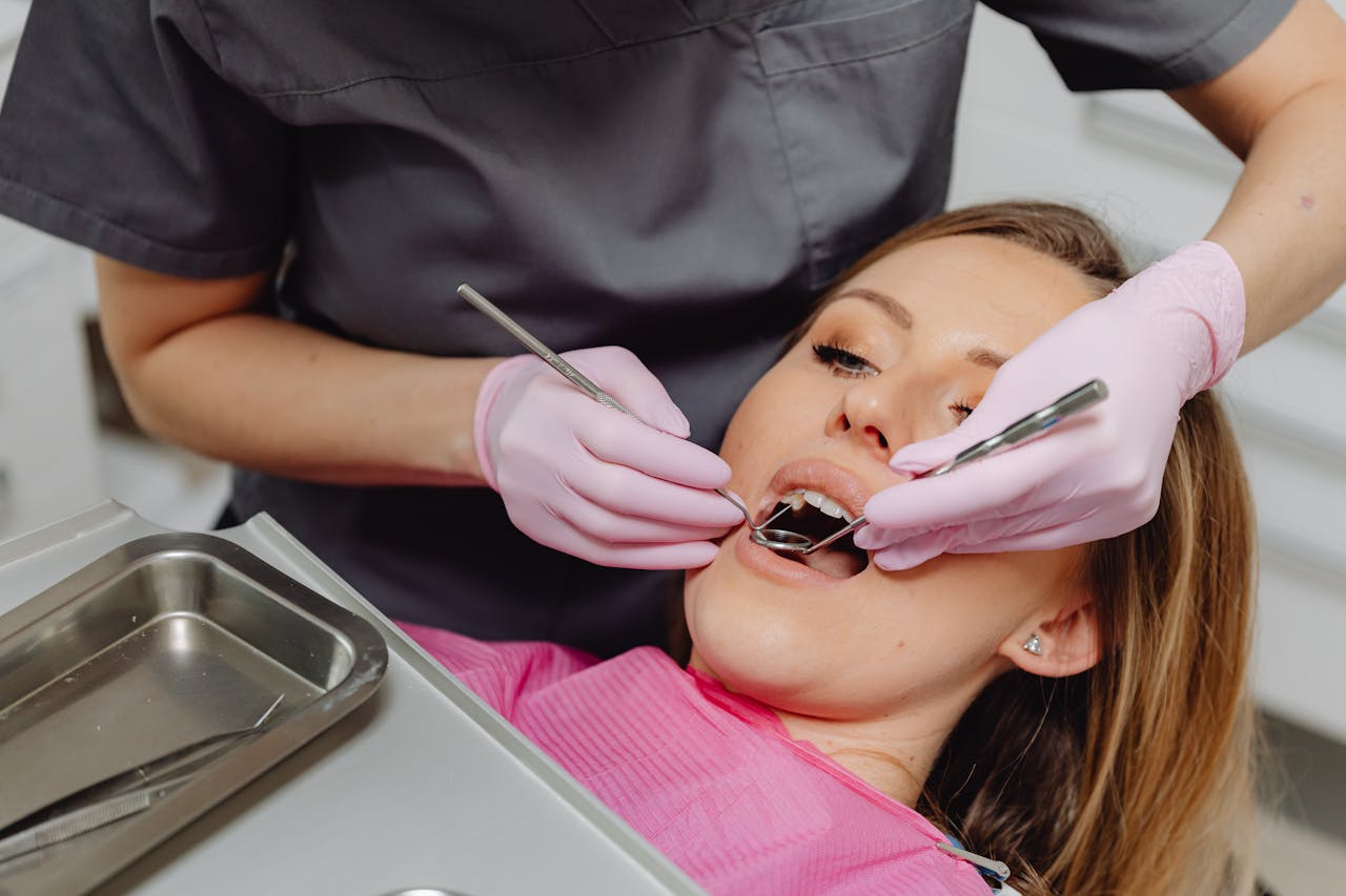 Dentist performing check-up on female patient in a clinic setting, emphasizing dental care.